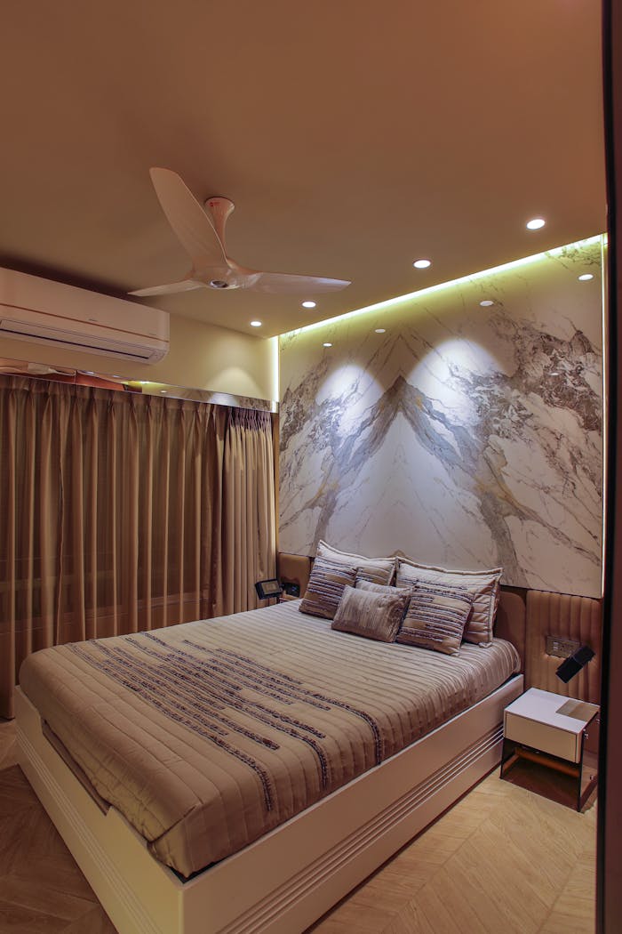 Home Stylish bedroom with ambient lighting and contemporary decor features a ceiling fan and artistic wall design.